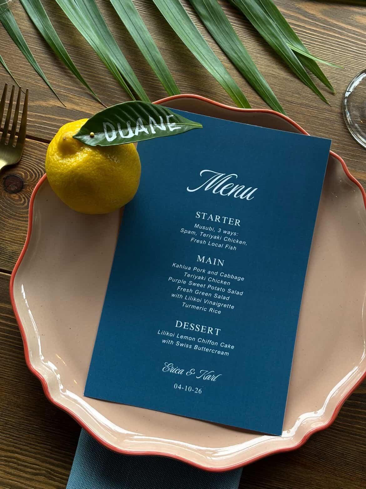 Blue wedding menu with a lemon on a plated place setting